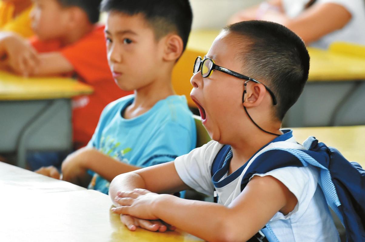 开学日，一名一年级学生坐在座位上打哈欠。新华社发